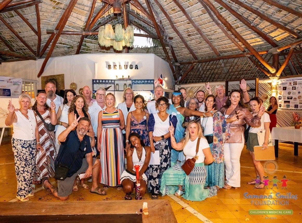A group gathered together beneath a thatched roof in a Samaná Smiles Foundation photograph