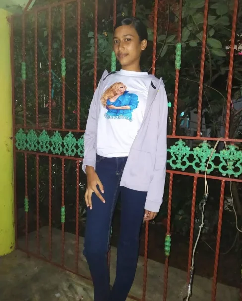 A girl in a light jacket standing beside a gate